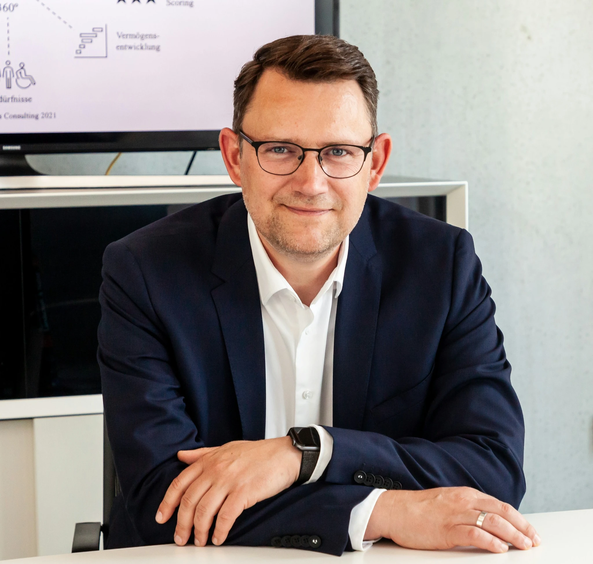 Man in suit and glasses sits at table